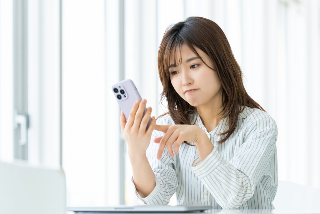 スマホを見て悩む女性